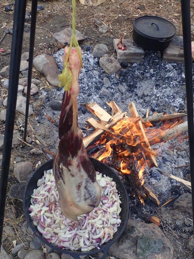 Roasting a deer leg over a fire.